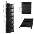 Green felt vertical wall garden planter with multiple planting pockets hung on an outdoor fence.