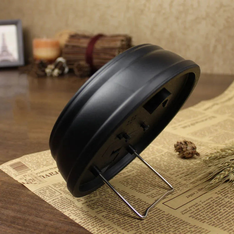 Round retro-style desk alarm clock with a white dial and silent sweep movement on a wooden surface.