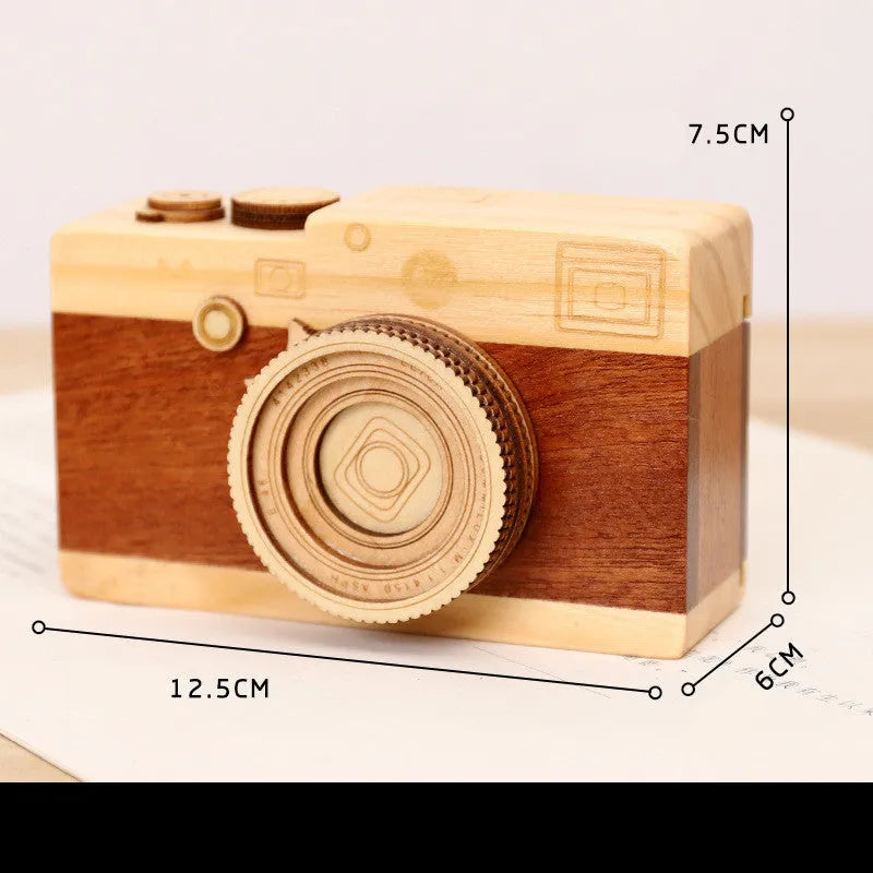 Pine wood camera-shaped rotating music box in decorative gift packaging.