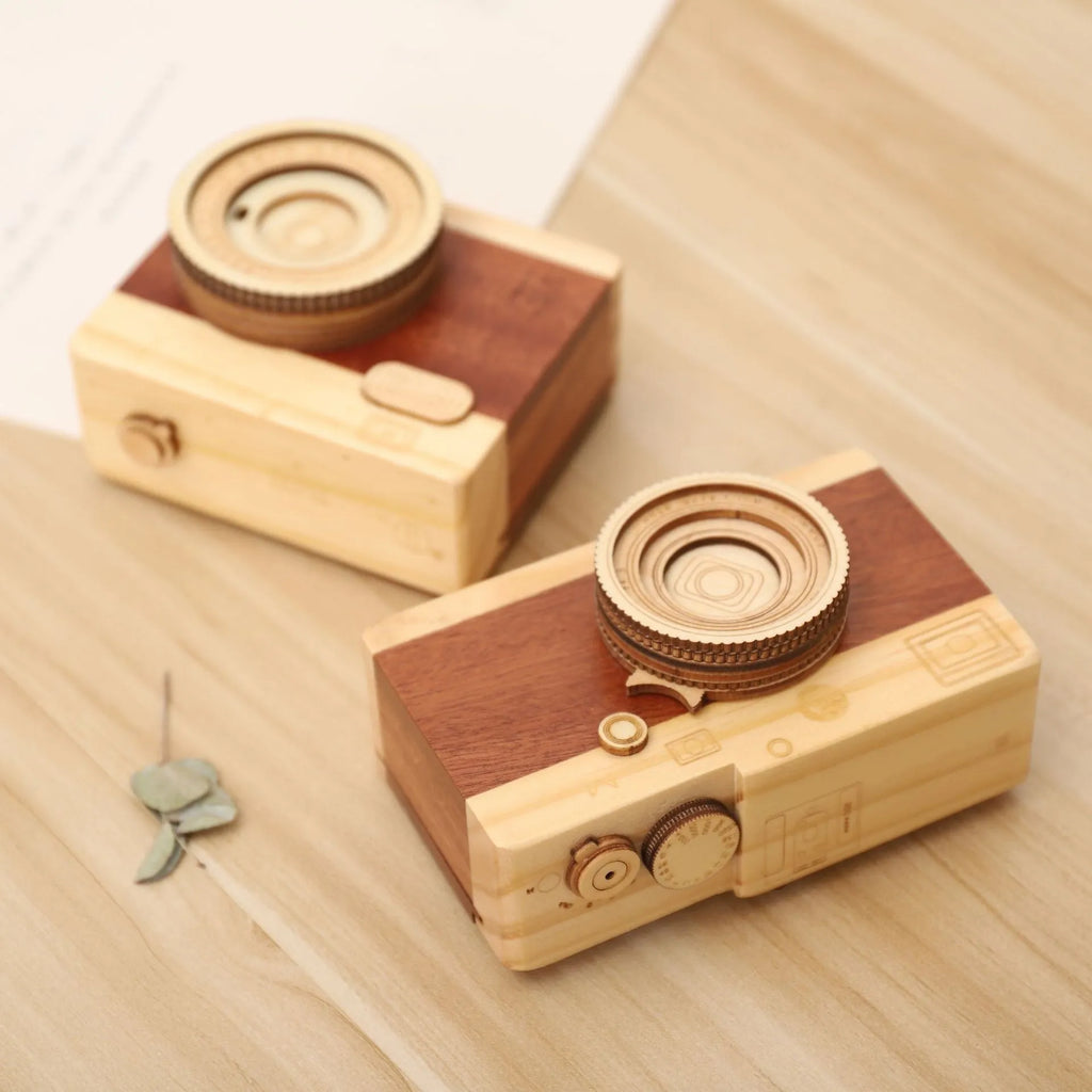 Pine wood camera-shaped rotating music box in decorative gift packaging.