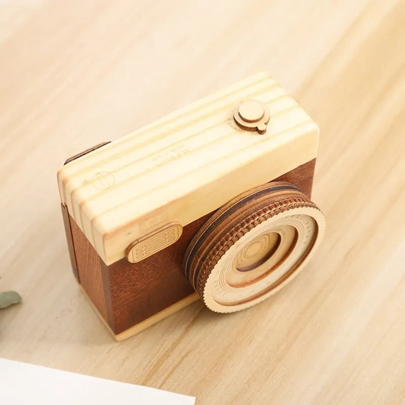 Pine wood camera-shaped rotating music box in decorative gift packaging.