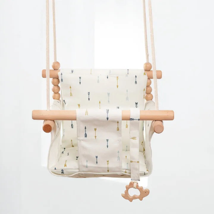 Cotton canvas baby swing chair with wooden seat and colourful tassel, hanging indoors.