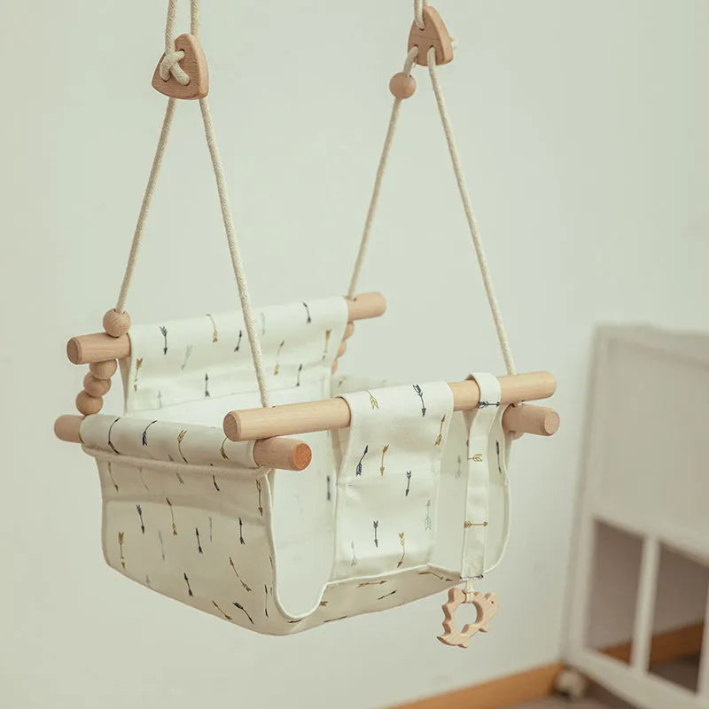 Cotton canvas baby swing chair with wooden seat and colourful tassel, hanging indoors.