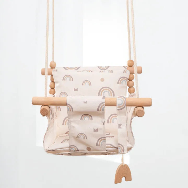 Cotton canvas baby swing chair with wooden seat and colourful tassel, hanging indoors.