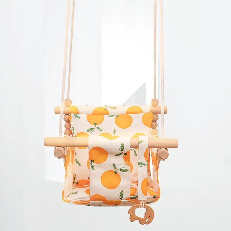 Cotton canvas baby swing chair with wooden seat and colourful tassel, hanging indoors.
