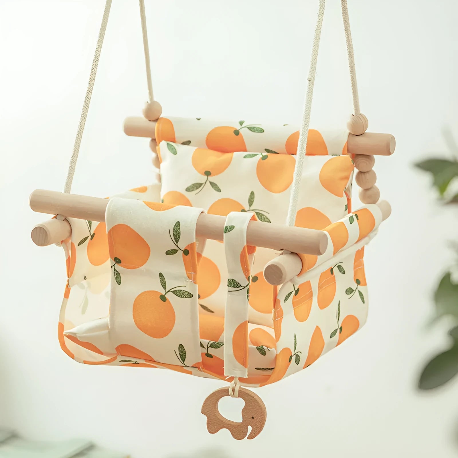 Cotton canvas baby swing chair with wooden seat and colourful tassel, hanging indoors.