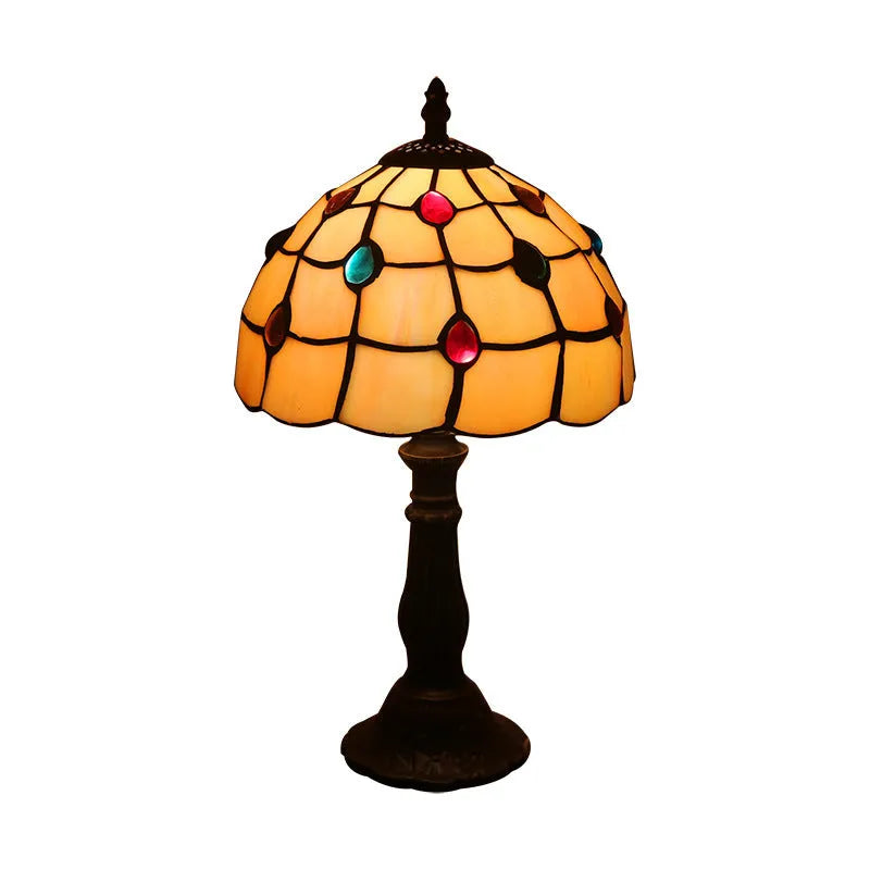 Yellow glass table lamp with mosaic pattern on a black resin base on a wooden table