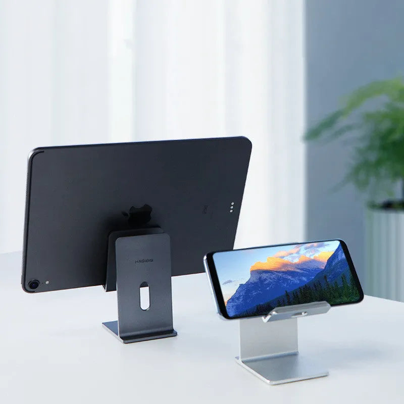 Dark Space Gray aluminium alloy adjustable lazy bracket phone holder clamped to a desk edge, holding a mobile phone.