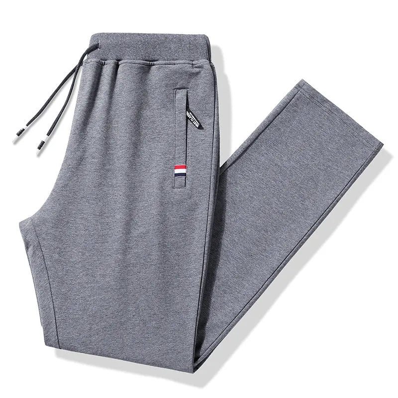 Pair of 95% cotton drawstring trousers in light grey, straight-leg nine-tenths length, laid flat on a plain background