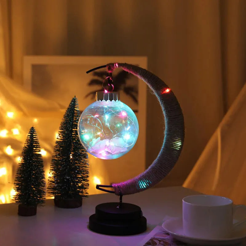 Moon ball shape LED night light with crescent holder, PVC shell, warm light on a wooden table