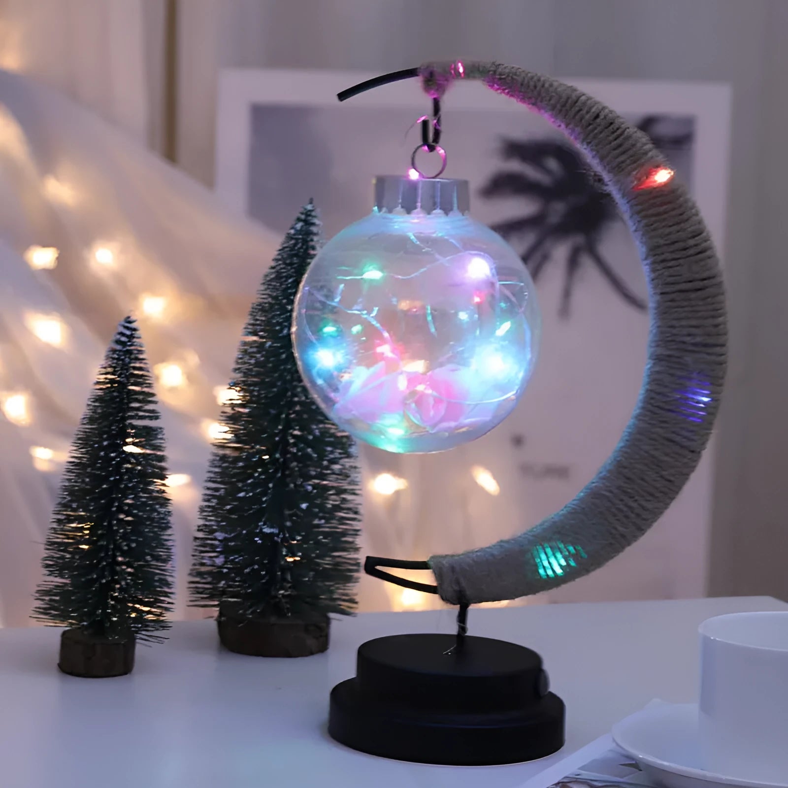 Moon ball shape LED night light with crescent holder, PVC shell, warm light on a wooden table