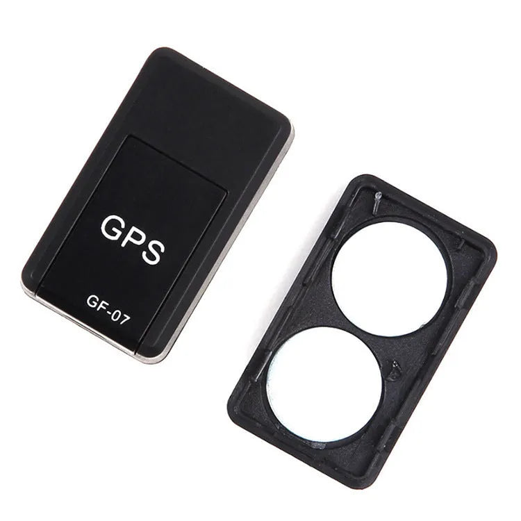 Small black magnetic GPS tracker device next to a micro-USB cable on a table.