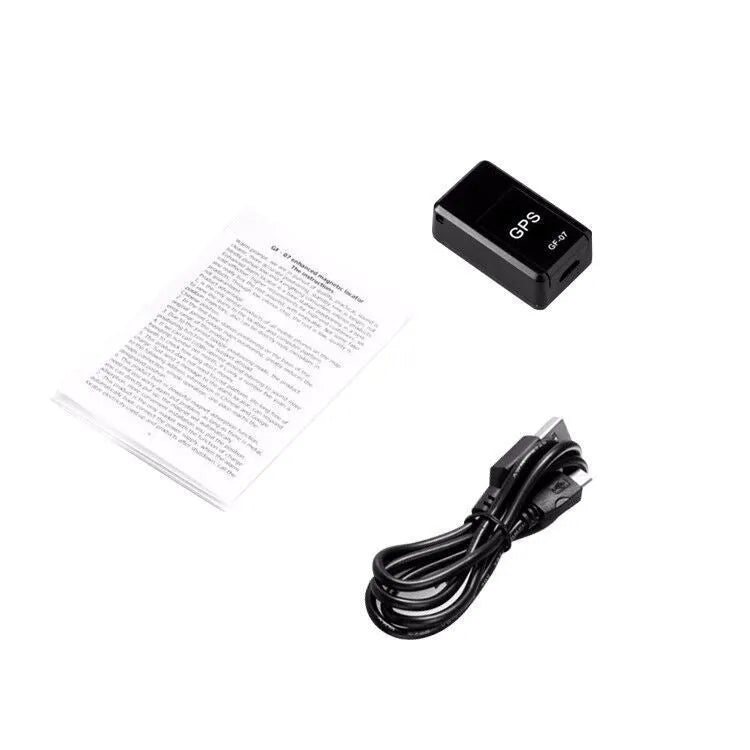 Small black magnetic GPS tracker device next to a micro-USB cable on a table.