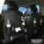Black PU leather car seat back organiser with multiple pockets hanging on a car headrest.