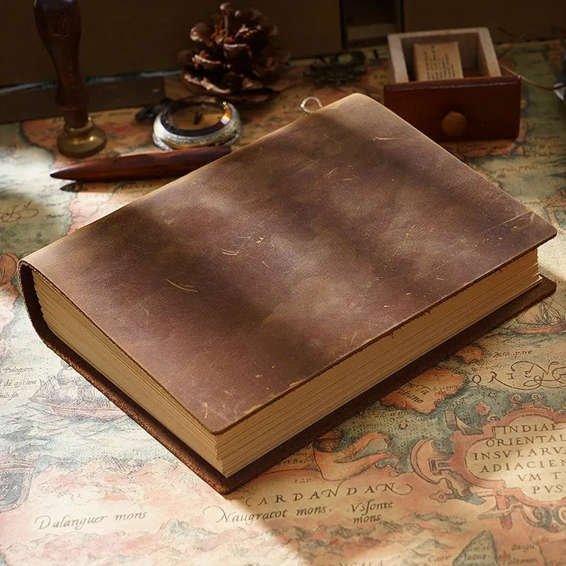 Brown handmade cowhide leather notebook with 200 pages, 19x14cm paper size, lying open on a wooden desk