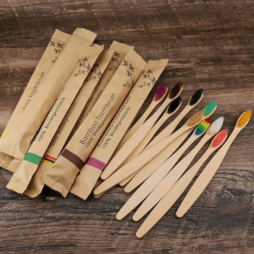10 multi-coloured natural bamboo toothbrushes with soft charcoal bristles arranged on a white background