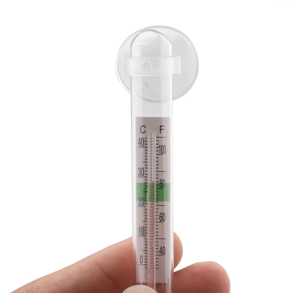 White glass aquarium fat thermometer with suction cup floating on water surface showing temperature scale