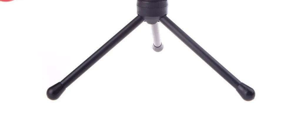 Black wired microphone with adjustable holder clip on a desk next to a laptop.