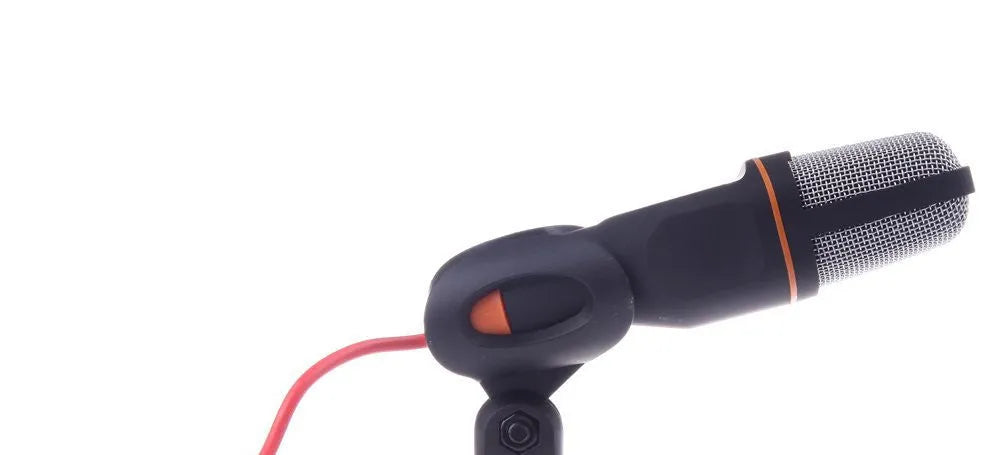 Black wired microphone with adjustable holder clip on a desk next to a laptop.