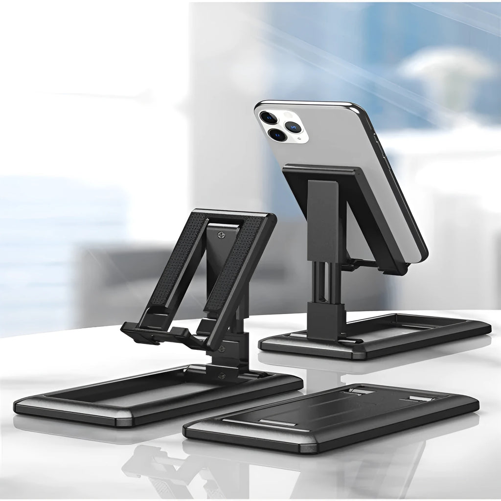 A folded and unfolded view of a black retractable mobile phone desktop stand on a wooden desk.