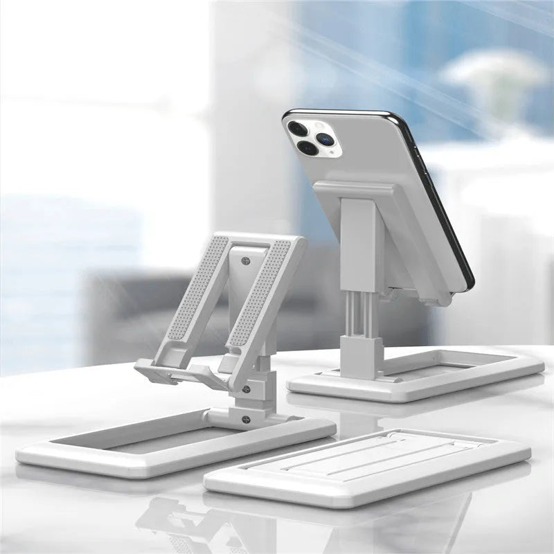 A folded and unfolded view of a black retractable mobile phone desktop stand on a wooden desk.