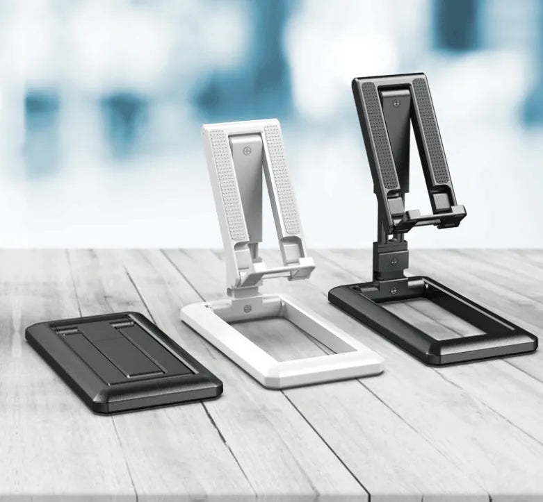 A folded and unfolded view of a black retractable mobile phone desktop stand on a wooden desk.