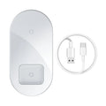 Baseus Minimalist Two-in-One Wireless Charging Pad in transparent finish on a wooden desk, charging a smartphone and AirPods case.