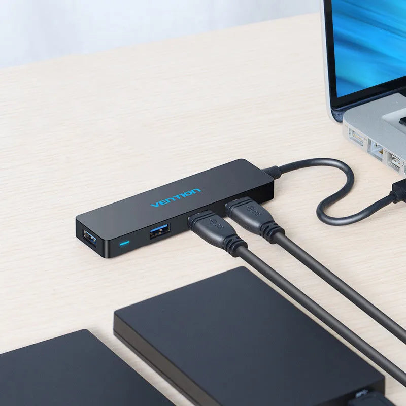 Black Wei Xun 4-port USB 3.0 hub with a short cable connected to a laptop