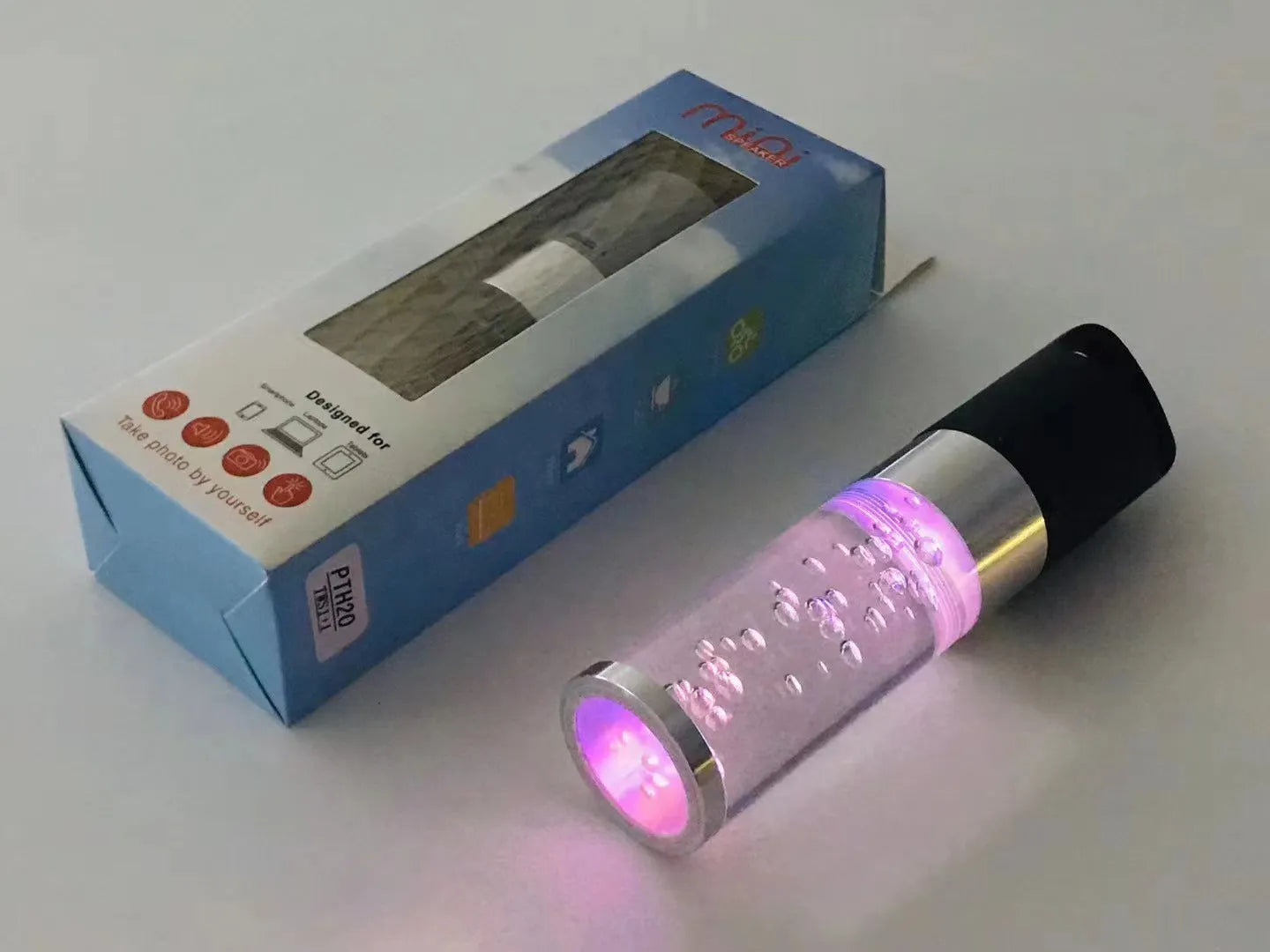 Pink portable Bluetooth speaker with a crystal light and carry handle on a white background.