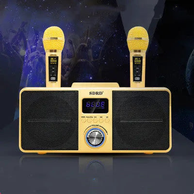 Black and gold Bluetooth karaoke speaker with two wireless microphones on a table.