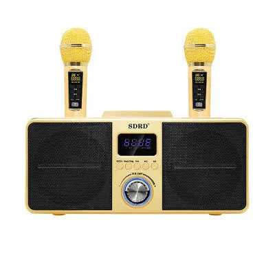 Black and gold Bluetooth karaoke speaker with two wireless microphones on a table.