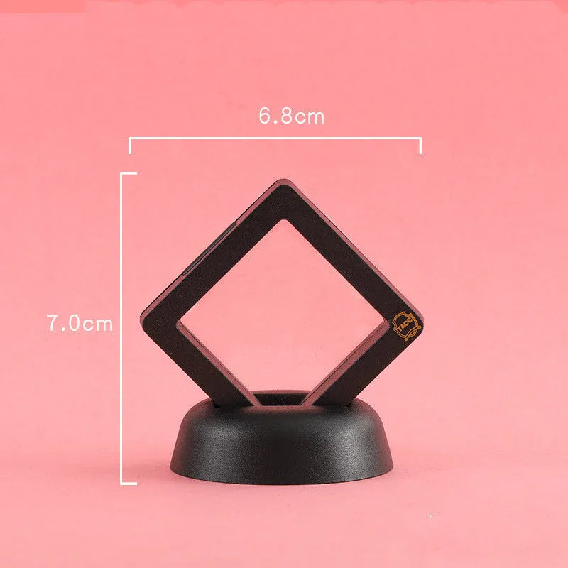 3D floating display case holding a coin suspended between transparent membrane sheets, black frame