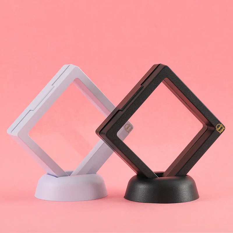 3D floating display case holding a coin suspended between transparent membrane sheets, black frame
