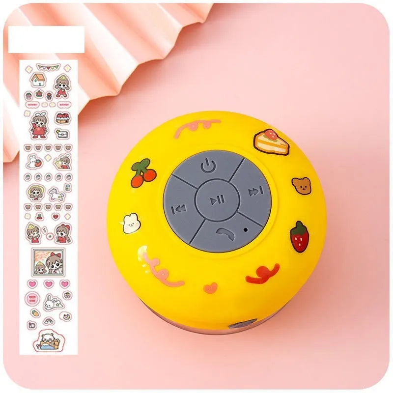 Small colourful waterproof Bluetooth speaker with a silicone suction cup base on a bathroom tile.