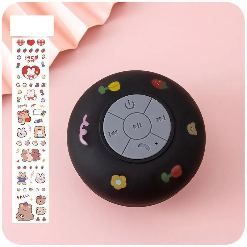 Small colourful waterproof Bluetooth speaker with a silicone suction cup base on a bathroom tile.