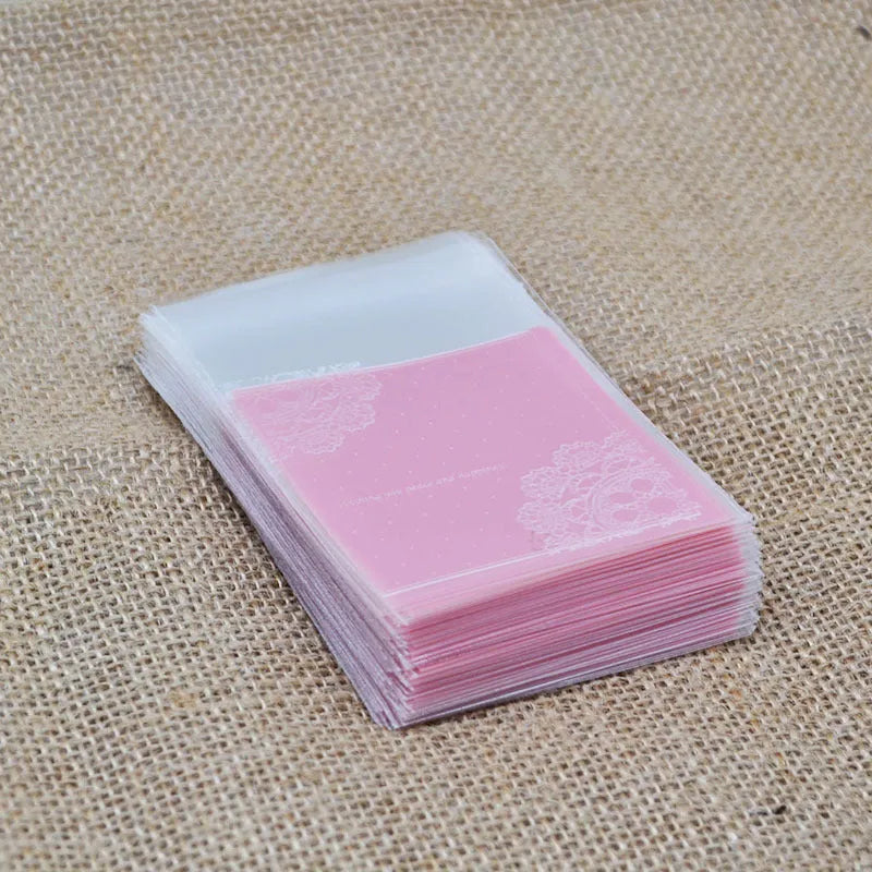 Clear self-adhesive plastic packaging bags with pink UV print, showing 7cm by 7cm size and gusset.