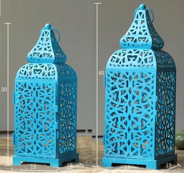 A blue hollow geometric iron candelabrum, 38cm tall, holding a candle on a wooden surface.