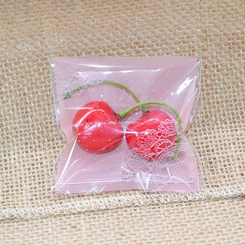 Clear self-adhesive plastic packaging bags with pink UV print, showing 7cm by 7cm size and gusset.