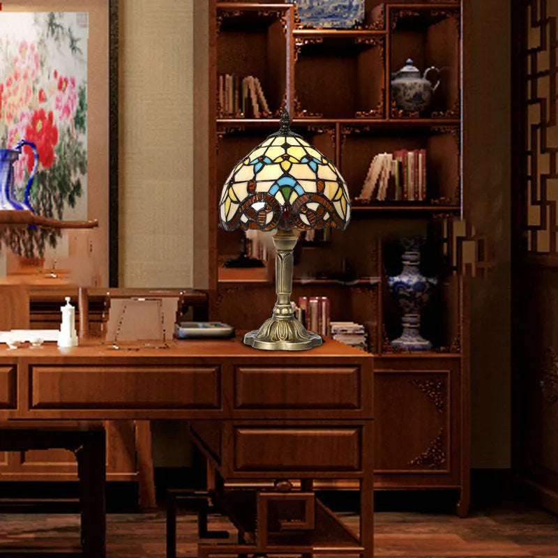 Yellow glass table lamp with mosaic pattern on a black resin base on a wooden table