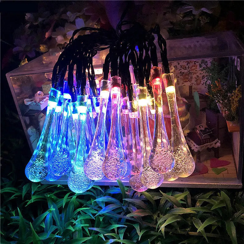 6.5 metre long solar-powered outdoor string lights with water drop shaped pendants on a green lawn.