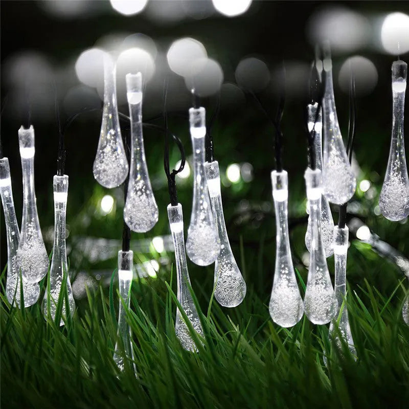 6.5 metre long solar-powered outdoor string lights with water drop shaped pendants on a green lawn.