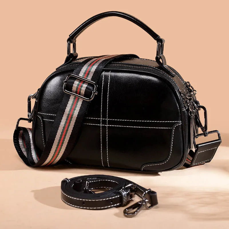 Round women's leather handbag with soft handle and zipper closure in wine red colour