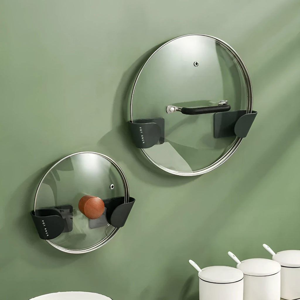 Simple wall-mounted non-punching pot cover rack in black, ABS plastic, 16.5x5x4.5cm, holding pot lids on a kitchen wall