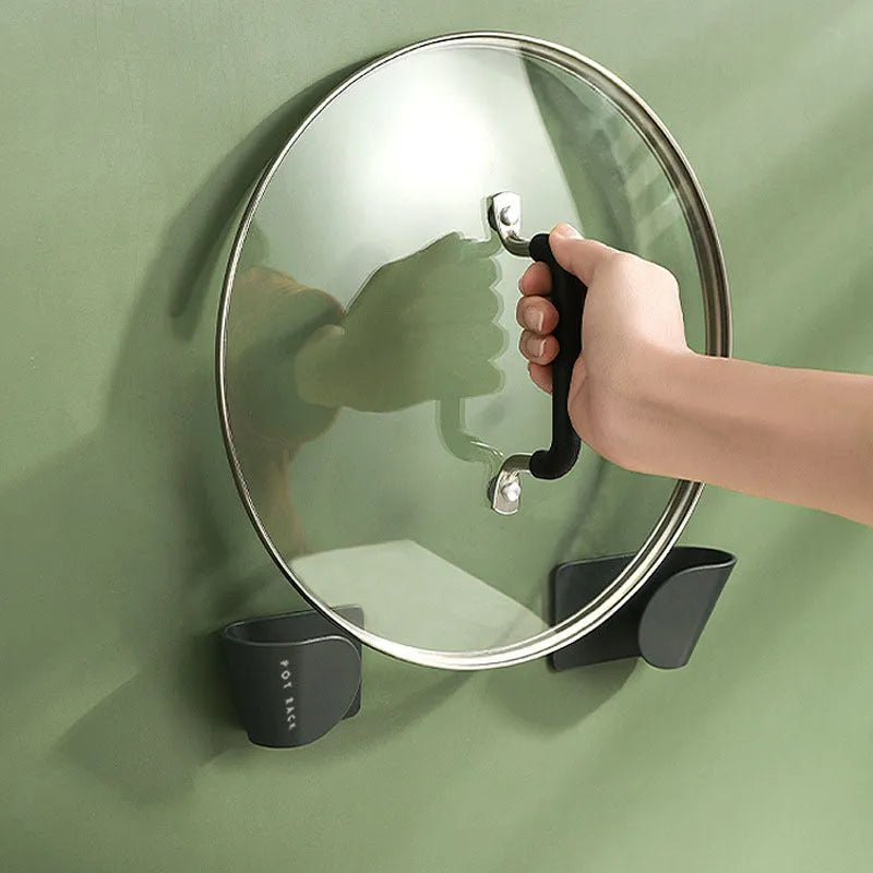 Simple wall-mounted non-punching pot cover rack in black, ABS plastic, 16.5x5x4.5cm, holding pot lids on a kitchen wall