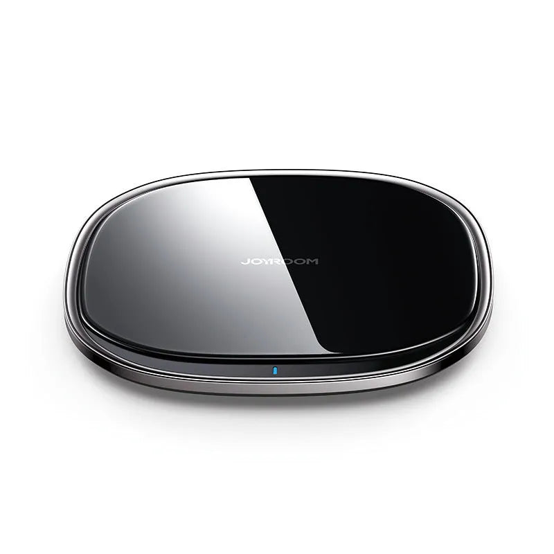 Black square 15W Qi wireless charging pad on a wooden desk next to a mobile phone.