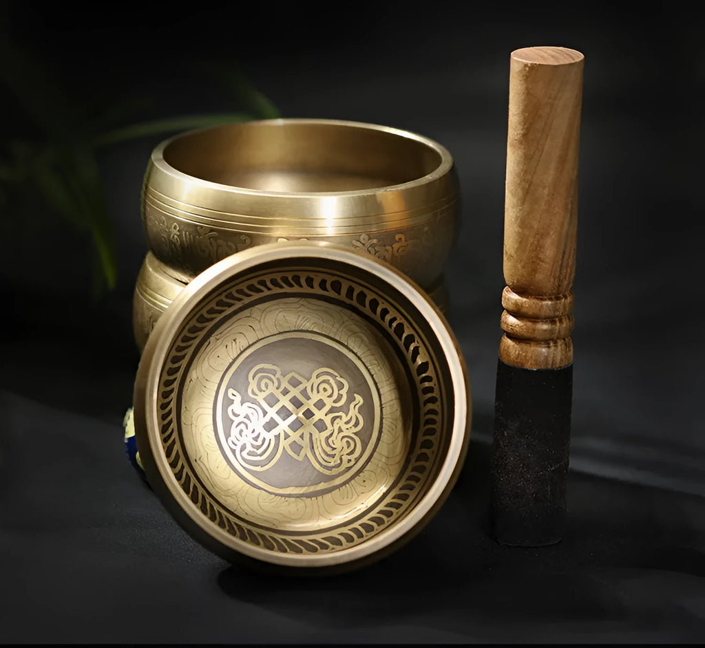 Handmade copper singing bowl with auspicious knot design on a soft surface with leather stick