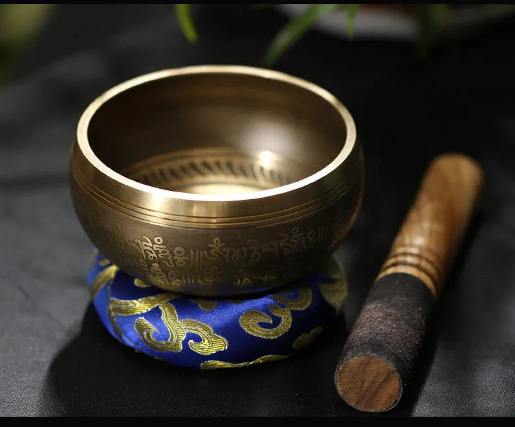 Handmade copper singing bowl with auspicious knot design on a soft surface with leather stick