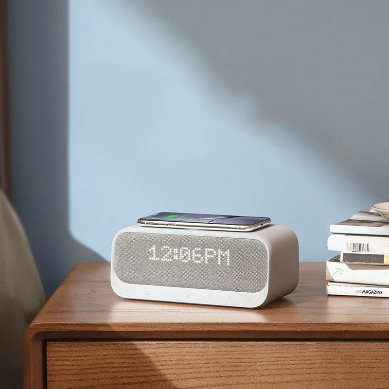 White Anker Soundcore Bluetooth speaker with wireless charging pad and digital clock display