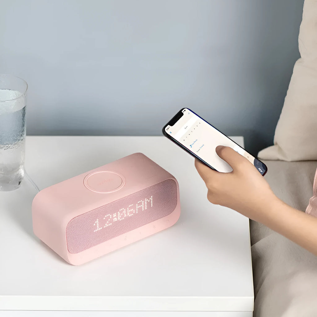 White Anker Soundcore Bluetooth speaker with wireless charging pad and digital clock display