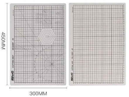 Green A3 self-healing cutting mat with centimetre grid lines on a wooden desk.